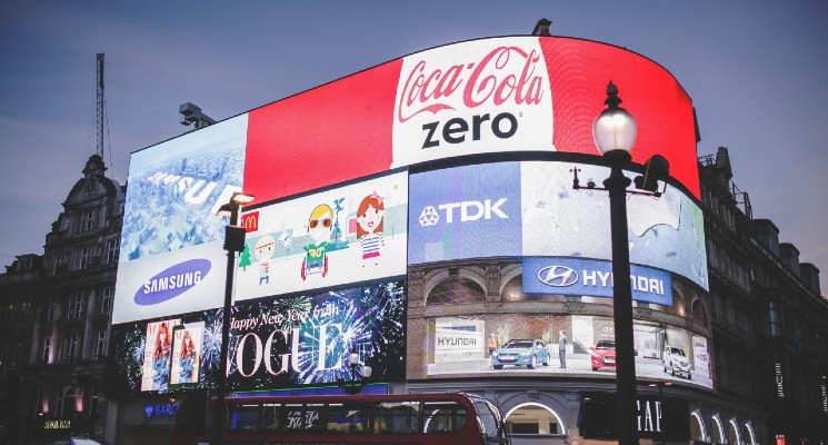 loads of adverts on billboard in london subliminal advertising blog header