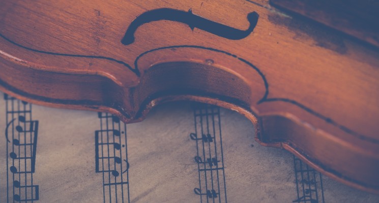 violin lying on manuscript classical music in commercials blog header