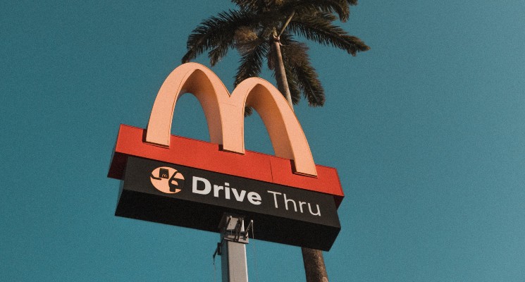 McDonalds Drive Thru sign against blue sky and palm tree