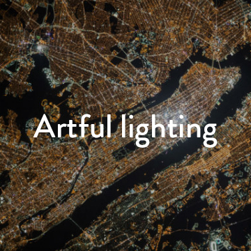 An aerial shot of a city at night lit up with white text reading 'Artful Lighting'